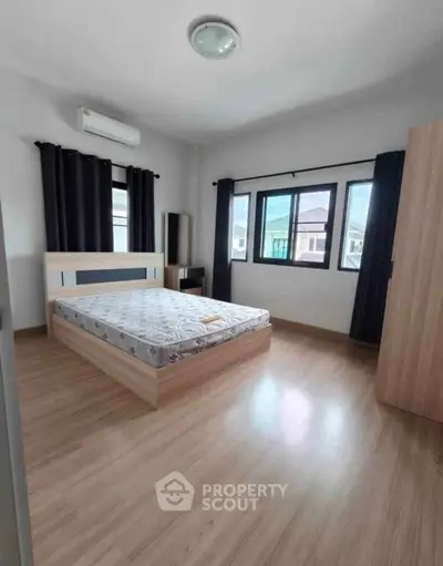 Spacious bedroom with large windows and modern furnishings in a bright, airy apartment.
