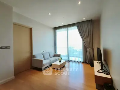 Modern living room with sleek furniture and large window offering natural light.