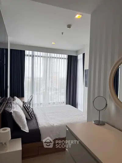 Modern bedroom with large windows and stylish decor in a high-rise apartment.