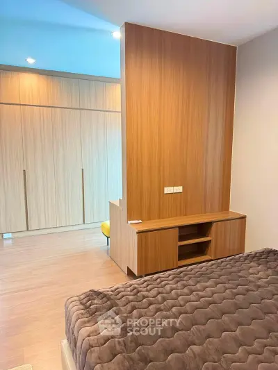 Modern bedroom with wooden accents and cozy bedding in a stylish apartment.
