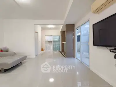 Spacious modern living room with sleek tile flooring and wall-mounted TV, perfect for relaxation and entertainment.