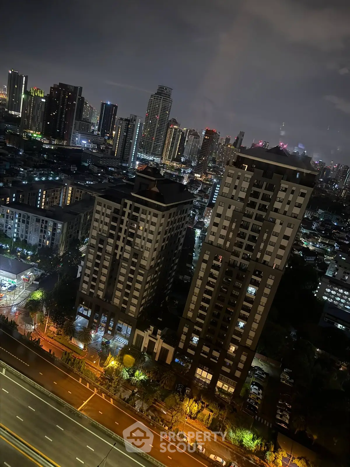 Stunning nighttime cityscape view from high-rise apartment overlooking vibrant urban skyline.