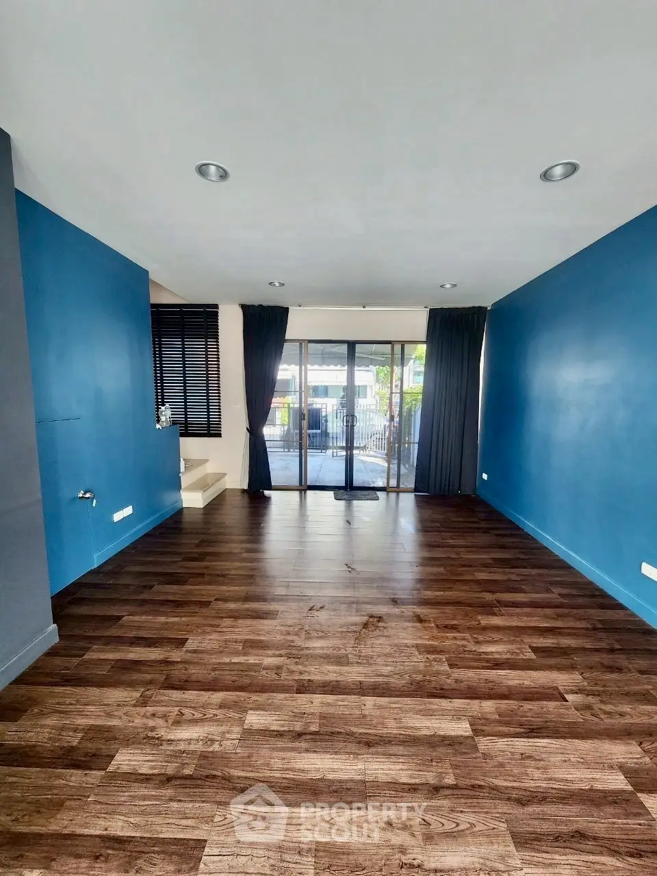 Spacious living room with wooden flooring and large windows for natural light.