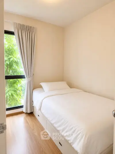 Cozy bedroom with single bed and large window offering lush green view, perfect for relaxation.