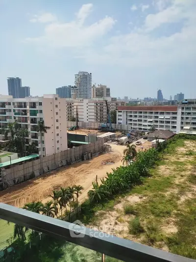 Stunning cityscape view from a high-rise balcony overlooking urban development and lush greenery.