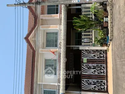 Charming two-story house with gated entrance and lush potted plants