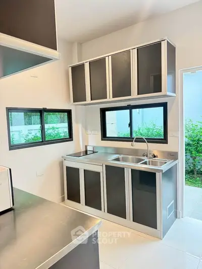 Modern kitchen with sleek black cabinets and large windows