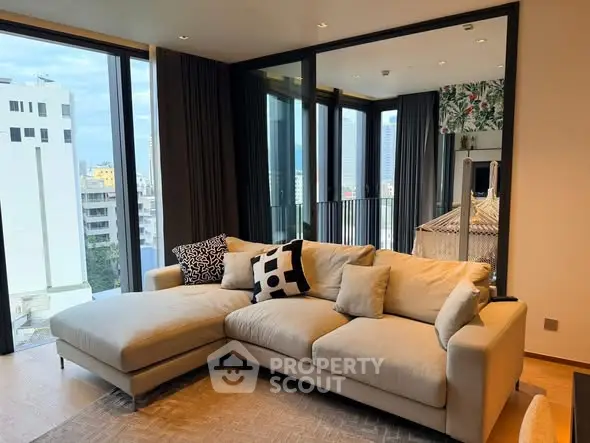 Modern living room with large beige sectional sofa and city view balcony.