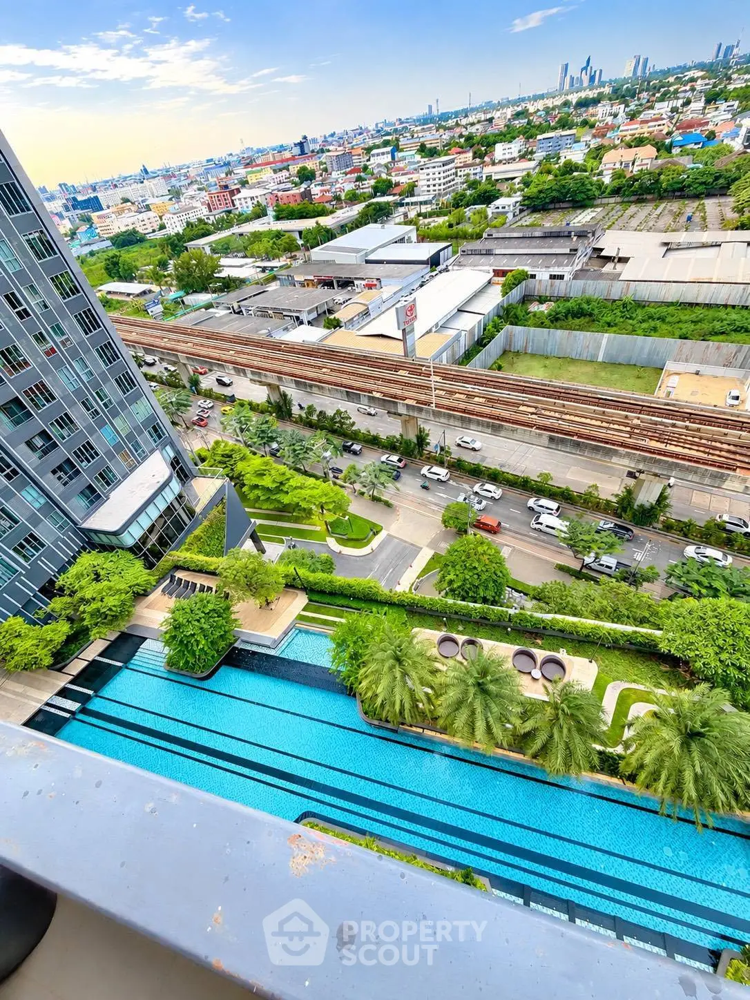Stunning city view from high-rise building with luxurious pool and lush greenery.