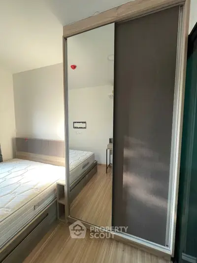 Modern bedroom with mirrored sliding wardrobe and wooden flooring
