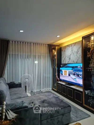 Modern living room with plush gray sofa, large TV, and elegant decor
