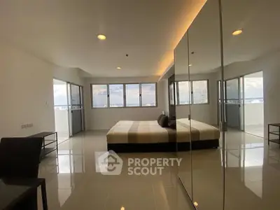 Spacious modern bedroom with large windows and sleek design in high-rise apartment.