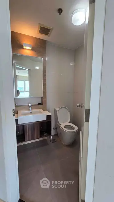 Modern bathroom with sleek fixtures and large mirror in a contemporary apartment.