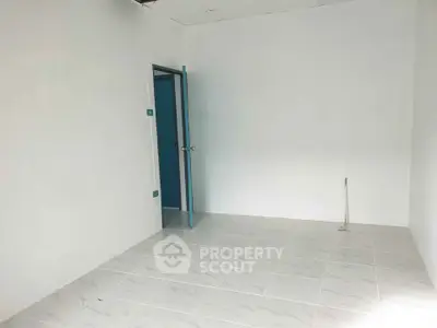 Spacious empty room with tiled floor and open door