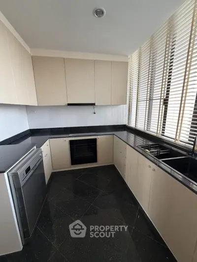 Modern kitchen with sleek black countertops and built-in appliances in a stylish apartment.