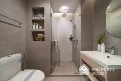 Modern bathroom with glass shower, sleek vanity, and built-in shelving for a stylish and functional design.