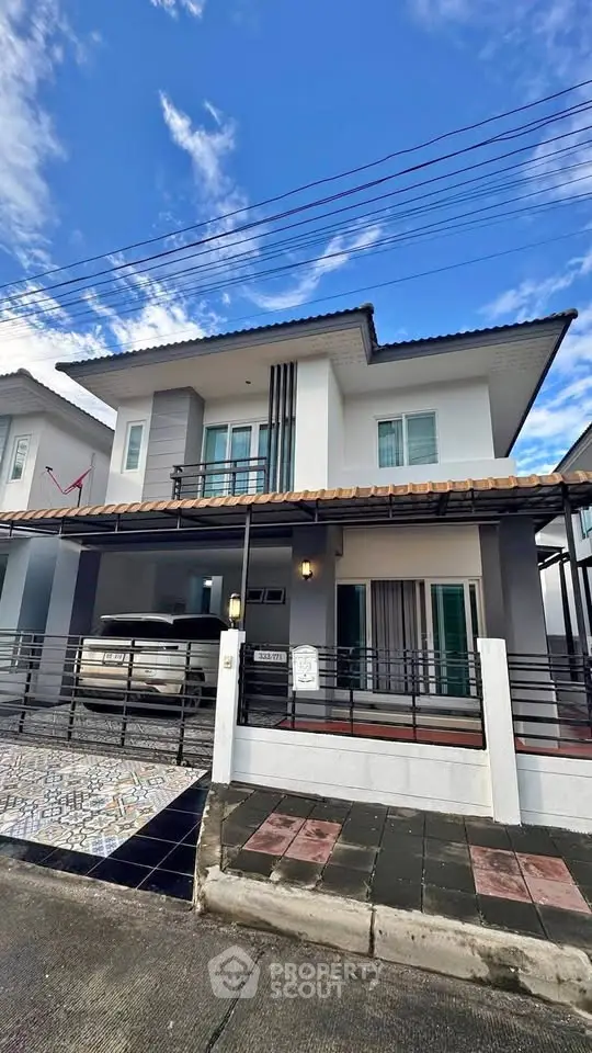 Modern two-story house with carport and stylish facade under a clear blue sky.