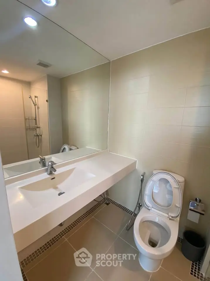 Modern bathroom with sleek fixtures and large mirror in a contemporary apartment.