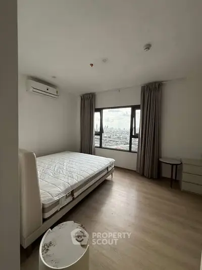 Spacious bedroom with city view, featuring a large window and modern furnishings.