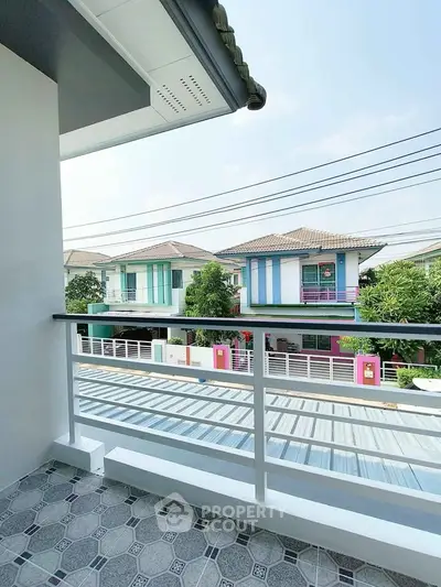 Charming balcony view of suburban homes with clear skies and modern railing.