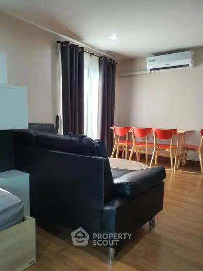 Modern living room with black leather sofa and dining area