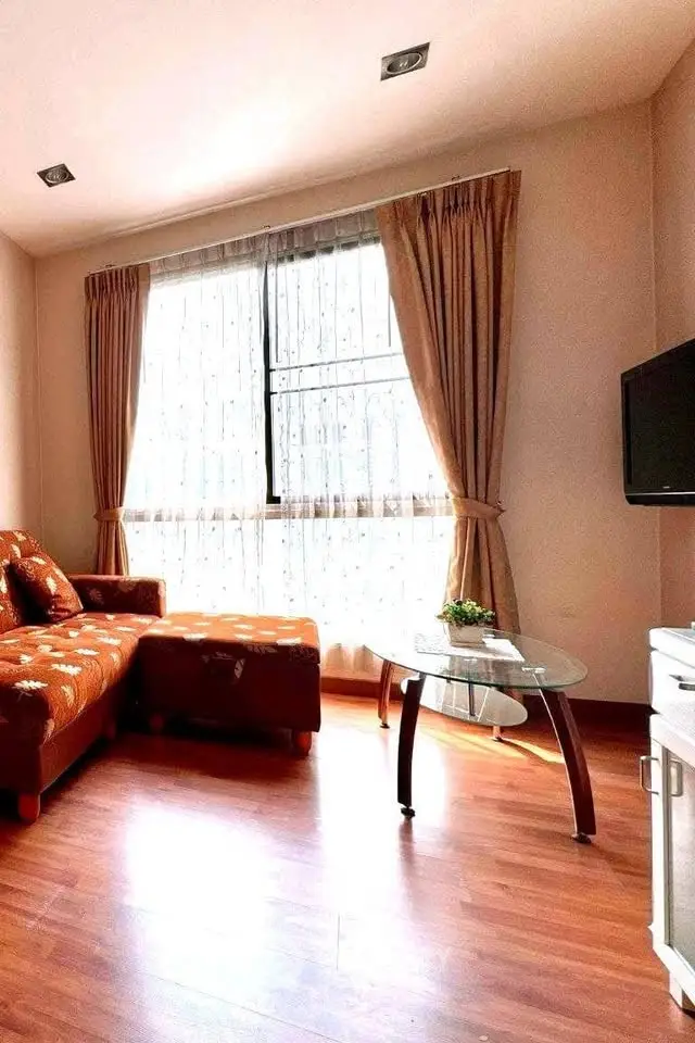 Bright living room with large window, cozy sofa, and modern TV setup.