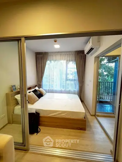 Modern bedroom with large window and balcony access in a stylish apartment.