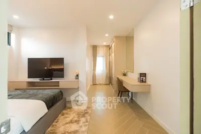 Modern bedroom with sleek design, featuring a cozy bed, flat-screen TV, and elegant workspace.