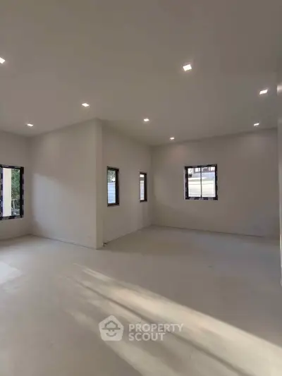 Spacious modern living room with ample natural light and sleek recessed lighting.