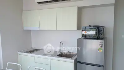Modern compact kitchen with sleek cabinetry, stainless steel fridge, and built-in appliances in a cozy apartment.