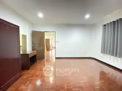 Spacious empty room with wooden flooring and modern lighting, ideal for customization.