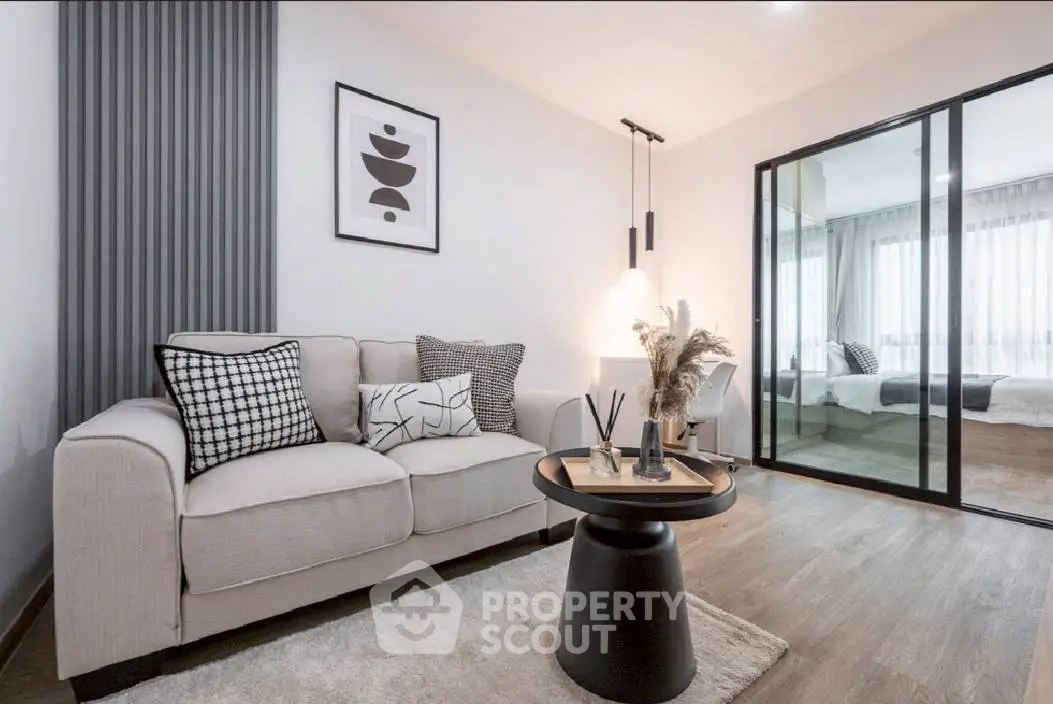 Modern living room with stylish decor and cozy seating area, featuring a view into a chic bedroom.