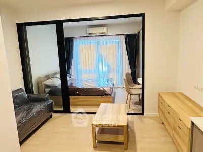 Modern apartment interior with glass partition separating living room and bedroom.