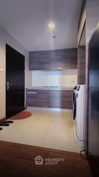 Modern kitchen with sleek cabinetry and washing machine in compact apartment.