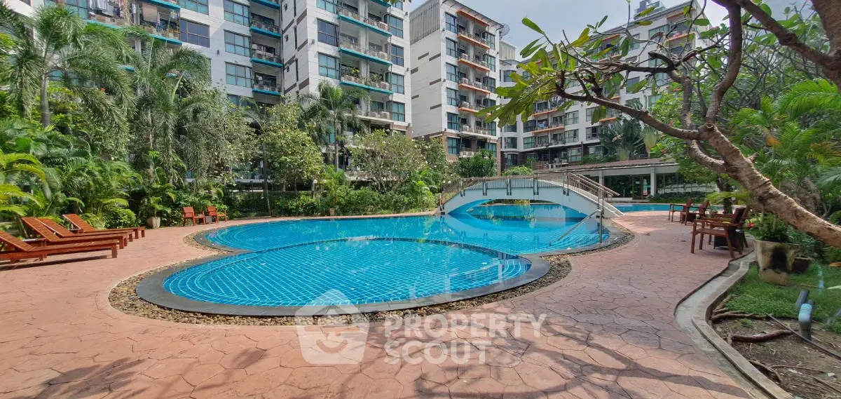 Luxurious apartment complex with stunning pool and lush garden surroundings.