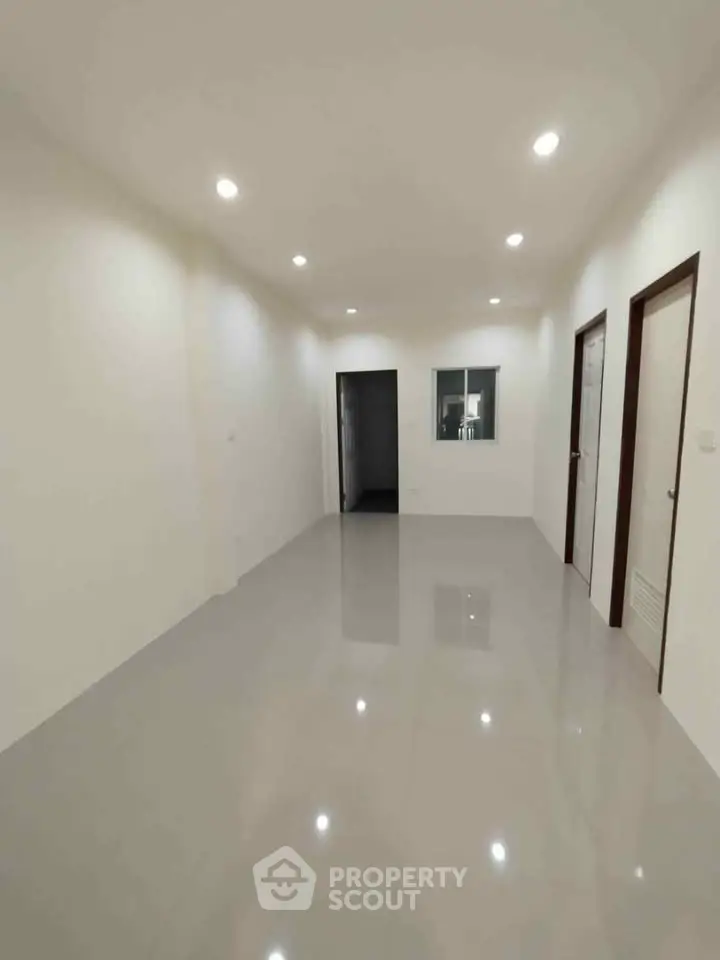 Spacious empty room with glossy tiled floor and recessed lighting, ideal for customization.