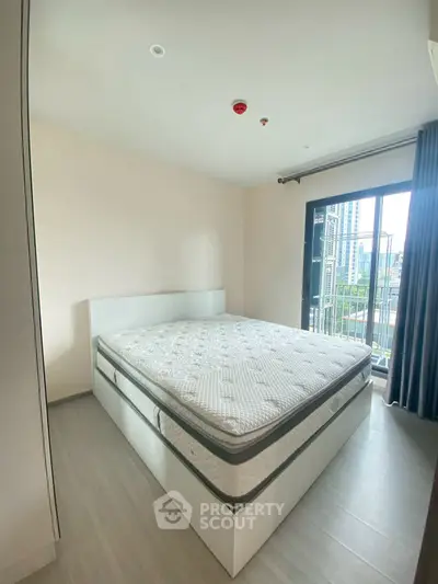 Modern bedroom with large window and city view, featuring a comfortable bed and sleek design.