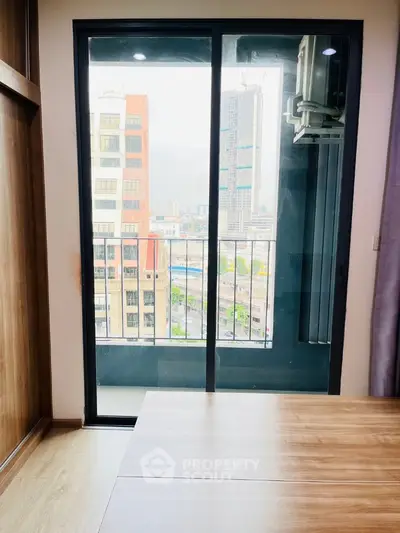 Modern apartment with balcony and city view, featuring sleek wooden flooring and large glass doors.