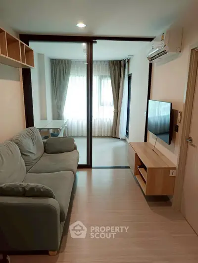 Modern living room with glass partition, cozy sofa, and wall-mounted TV in a stylish apartment.