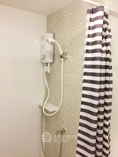 Modern bathroom with electric shower and striped curtain