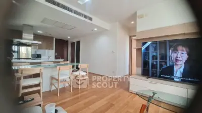 Modern open-layout living room with kitchen, featuring wooden flooring and stylish furniture.