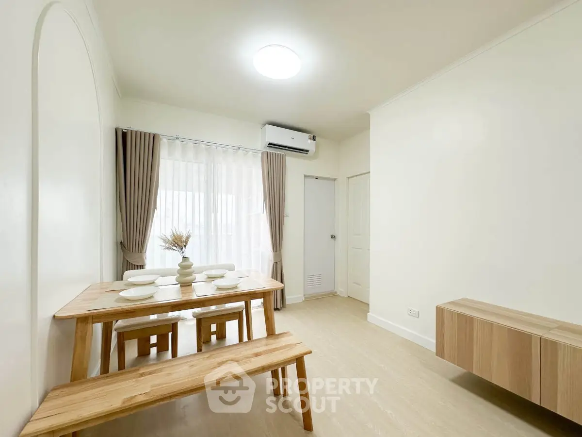 Bright dining area with wooden table and benches, featuring modern minimalist design and natural light.