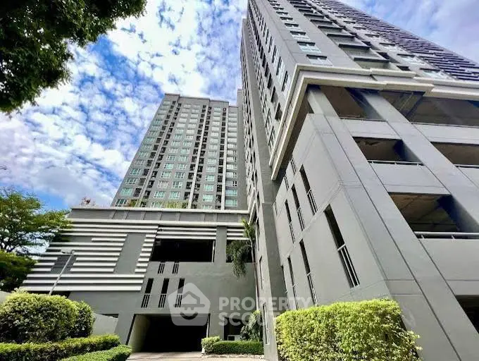 Modern high-rise building with lush greenery and clear blue sky