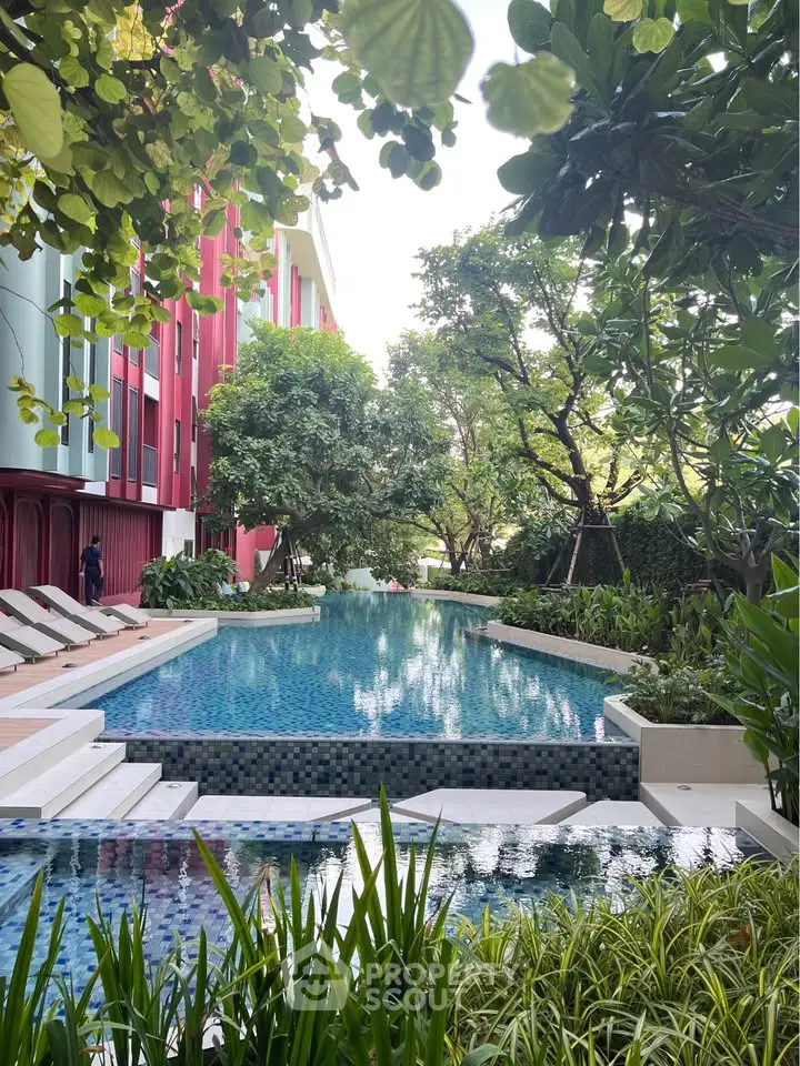 Luxurious outdoor pool surrounded by lush greenery and modern architecture, perfect for relaxation and leisure.