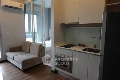 Modern compact apartment with open kitchen and cozy living area, featuring sleek appliances and stylish decor.