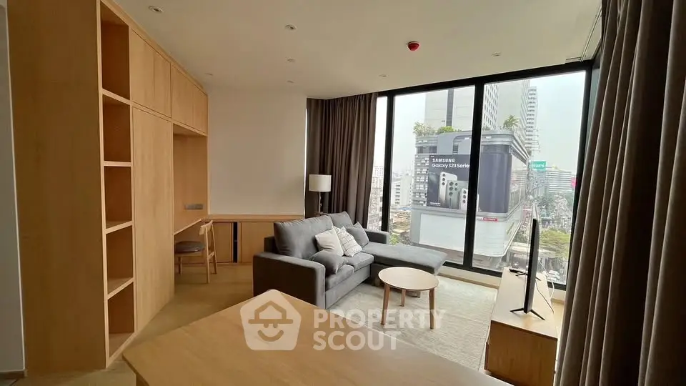 Modern living room with city view, featuring sleek furniture and large windows.