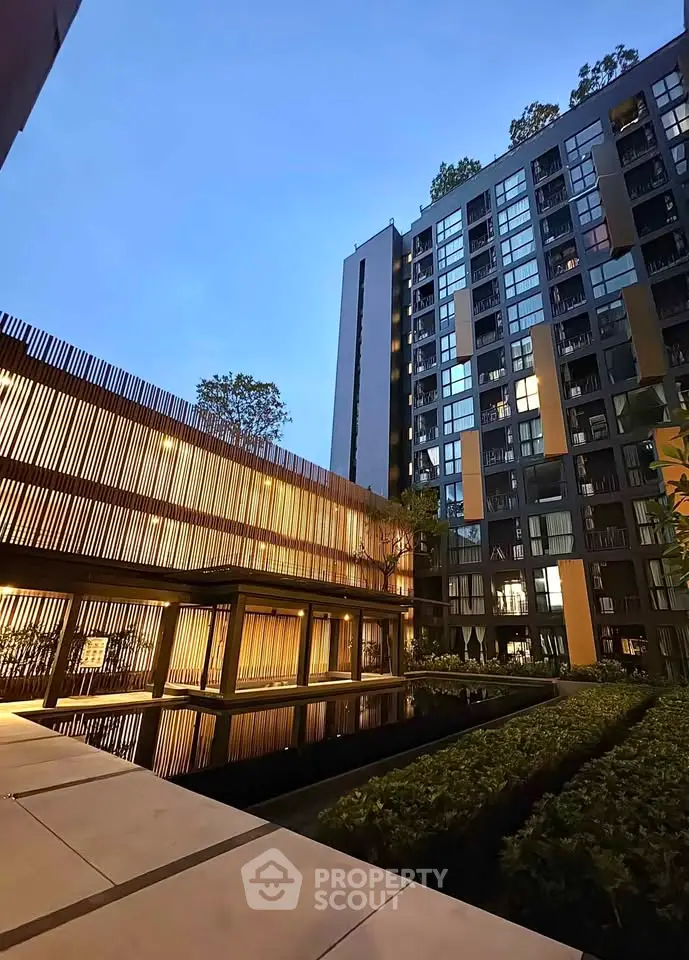 Modern apartment building with sleek design and lush greenery at dusk.