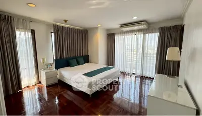 Spacious bedroom with large windows and elegant decor in a modern apartment.