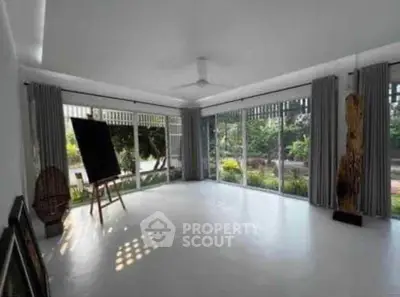 Spacious living room with large windows and garden view, perfect for art enthusiasts.