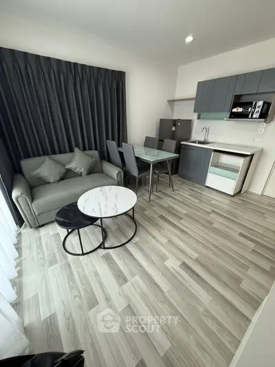 Modern living room with sleek kitchen, stylish furniture, and elegant flooring in a contemporary apartment.